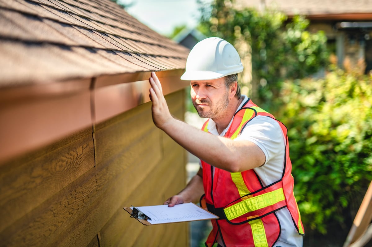 Roofing inspector examining a house roof for damage