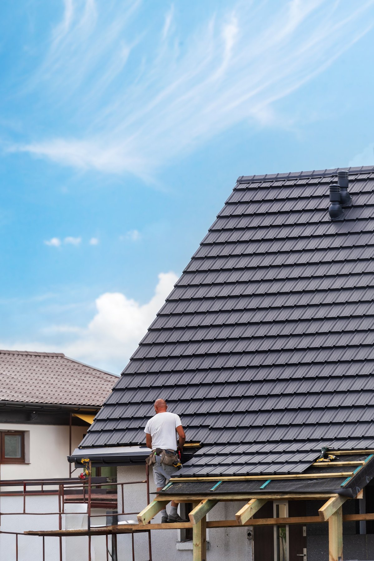 Roofer installing roofing tiles on a sloped roof