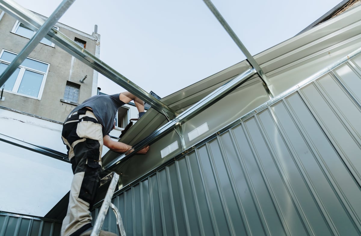 Roofer fastening a metal roofing sheet